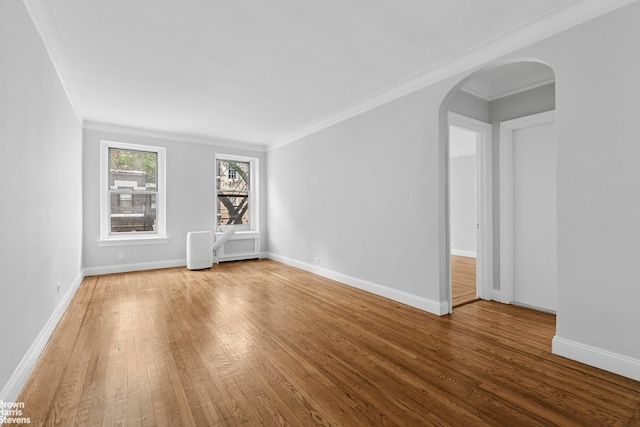 320 E 83rd St Unit 2B, New York City, NY 10028 - spare room with wood finished floors, arched walkways, ornamental molding, and radiator heating unit