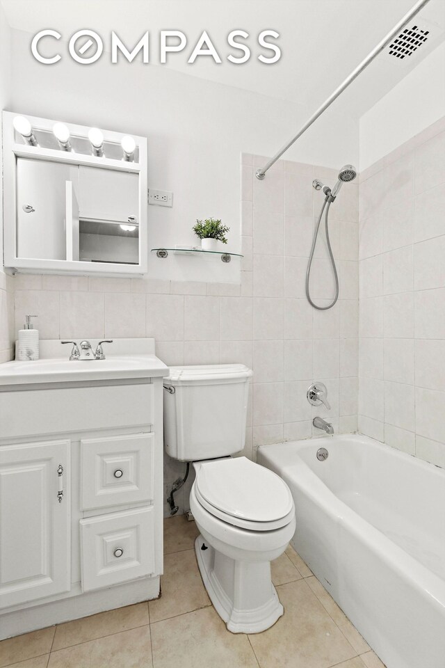 215 E 24th St Unit 412A, New York City, NY 10010 - bathroom featuring tile walls, vanity, tile patterned floors, and shower / bathtub combination