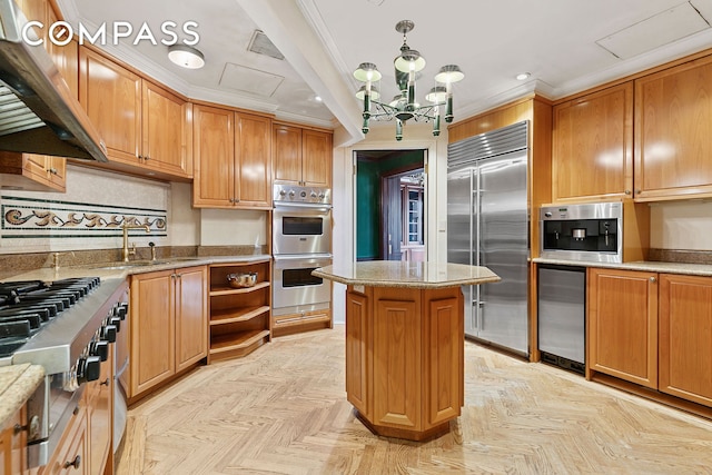 781 5th Ave Unit 17, New York City, NY 10022 - kitchen featuring stainless steel appliances, wall chimney exhaust hood, a chandelier, a center island, and light stone countertops