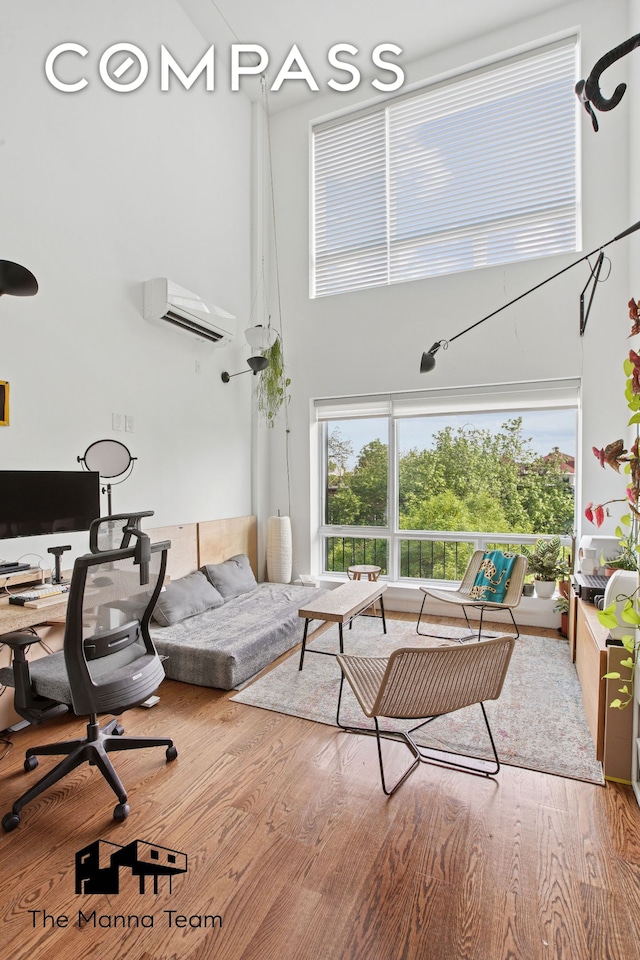 299 Van Buren St Unit 4C, New York City, NY 11221 - living area featuring a towering ceiling, a wall mounted AC, an office area, and wood finished floors