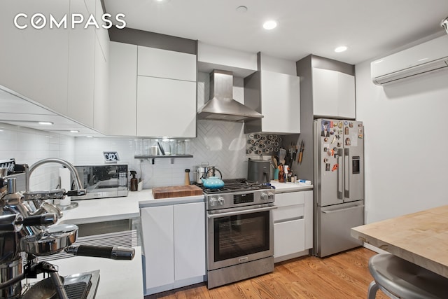 299 Van Buren St Unit 4C, New York City, NY 11221 - kitchen with stainless steel appliances, wall chimney range hood, an AC wall unit, light countertops, and modern cabinets