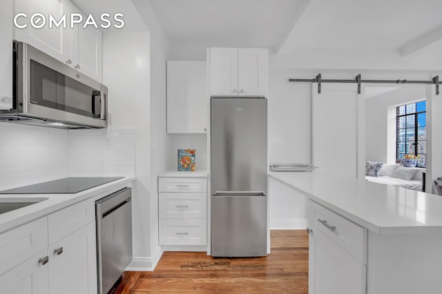25 Tudor City Pl Unit 1405, New York City, NY 10017 - kitchen with appliances with stainless steel finishes, light wood finished floors, light countertops, tasteful backsplash, and white cabinetry