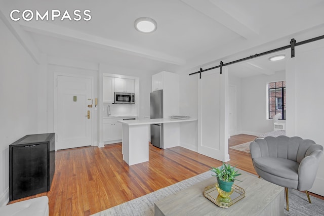 25 Tudor City Pl Unit 1405, New York City, NY 10017 - living area featuring a barn door, light wood-style flooring, and beamed ceiling
