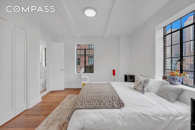 25 Tudor City Pl Unit 1405, New York City, NY 10017 - bedroom featuring wood finished floors, multiple windows, and beamed ceiling