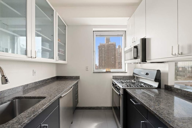 301 W 57th St Unit 27A, New York City, NY 10019 - kitchen featuring appliances with stainless steel finishes, plenty of natural light, glass insert cabinets, and dark stone countertops