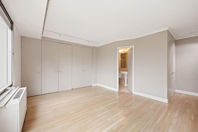 180 Park Row Unit 5B, New York City, NY 10038 - unfurnished bedroom featuring light wood-style floors, a closet, rail lighting, crown molding, and connected bathroom