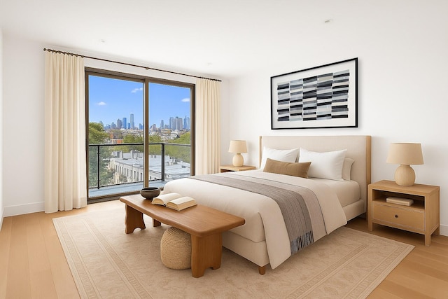 488 4th Ave Unit 6, New York City, NY 11215 - bedroom with access to exterior, light wood-style floors, a skyline view, and multiple windows