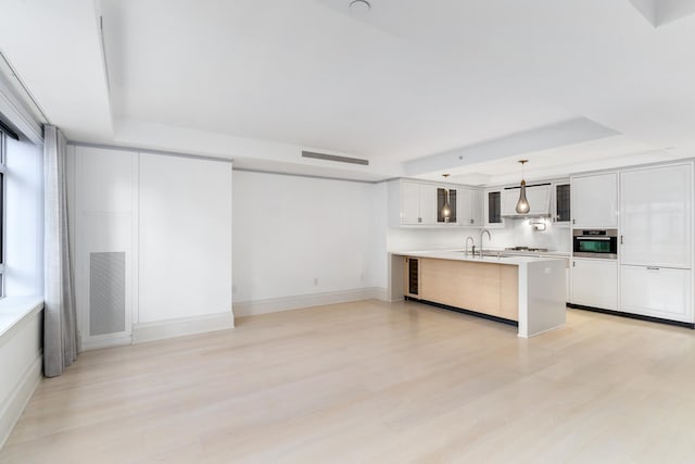21 E 61st St Unit 9C, New York City, NY 10065 - kitchen with a raised ceiling, ventilation hood, light wood-style floors, and glass insert cabinets