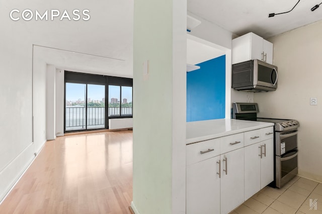 25-40 Shore Blvd Unit 4R, New York City, NY 11102 - kitchen featuring appliances with stainless steel finishes, light countertops, white cabinetry, a water view, and light wood-type flooring