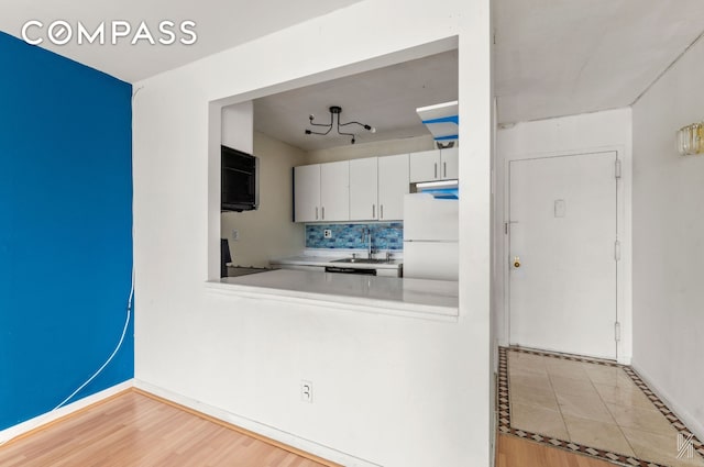 25-40 Shore Blvd Unit 4R, New York City, NY 11102 - kitchen with freestanding refrigerator, decorative backsplash, light countertops, white cabinets, and wood finished floors
