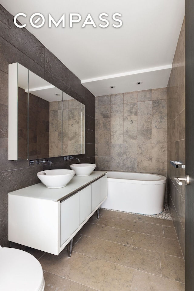 247 W 46th St Unit 3103, New York City, NY 10036 - bathroom featuring tile walls, double vanity, and a garden tub