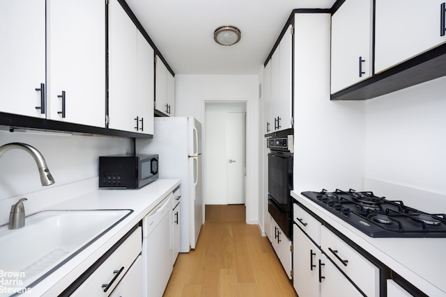 445 E 86th St Unit 12G, New York City, NY 10028 - kitchen featuring black appliances, light countertops, white cabinetry, light wood finished floors, and a warming drawer