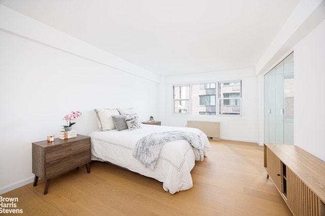 445 E 86th St Unit 12G, New York City, NY 10028 - bedroom with radiator, multiple windows, and light wood-style flooring