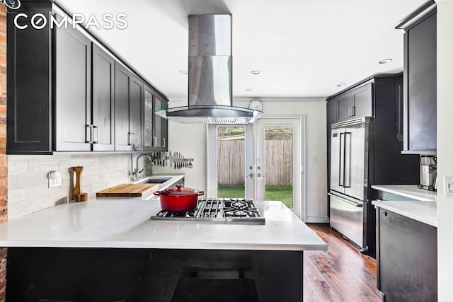 170 Skillman Ave, New York City, NY 11211 - kitchen featuring appliances with stainless steel finishes, island range hood, wood finished floors, light countertops, and tasteful backsplash