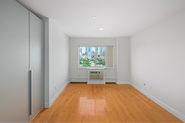 378 Baltic St Unit 9C, New York City, NY 11201 - unfurnished bedroom with a baseboard radiator, light wood-style flooring, an AC wall unit, and recessed lighting