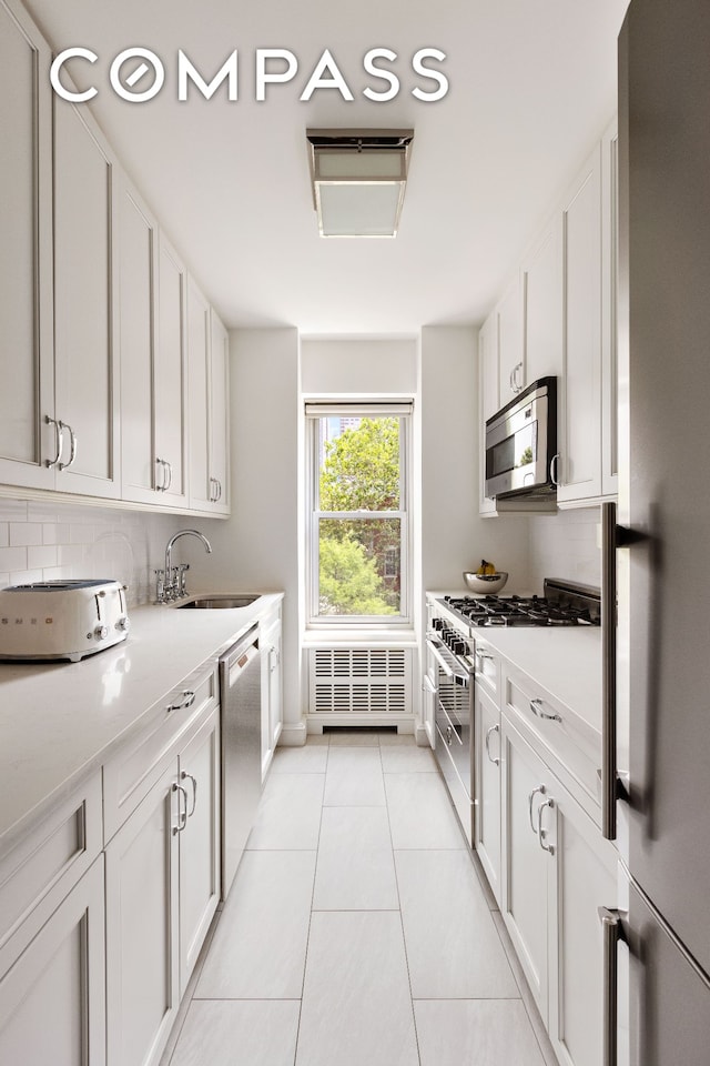 2 5th Ave Unit 5F, New York City, NY 10011 - kitchen featuring stainless steel appliances, light countertops, white cabinets, and radiator