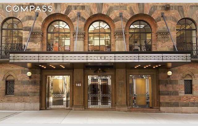 140 E 63rd St Unit 9E, New York City, NY 10065 - view of exterior entry with a balcony, brick siding, and french doors