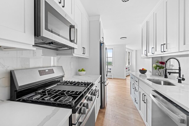 1655 Flatbush Ave Unit B1812, New York City, NY 11210 - kitchen featuring appliances with stainless steel finishes, light wood finished floors, white cabinetry, tasteful backsplash, and light stone counters