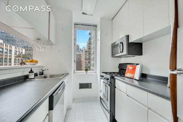 235 E 40th St Unit 11G, New York City, NY 10016 - kitchen featuring appliances with stainless steel finishes, white cabinets, a view of city, dark countertops, and light tile patterned floors