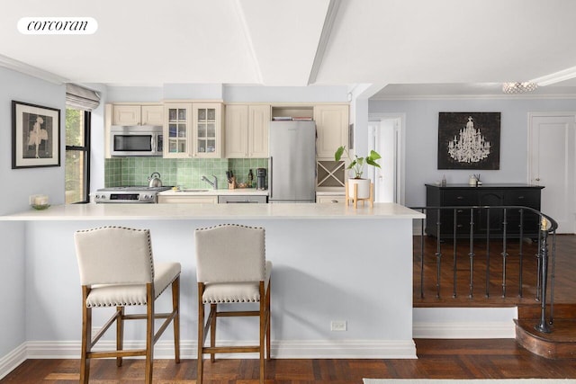 235 E 73rd St Unit 3E, New York City, NY 10021 - kitchen with stainless steel appliances, cream cabinetry, tasteful backsplash, a kitchen breakfast bar, and light countertops