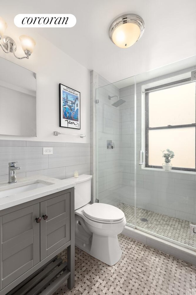 235 E 73rd St Unit 3E, New York City, NY 10021 - full bathroom featuring tile walls, a shower stall, vanity, and wainscoting