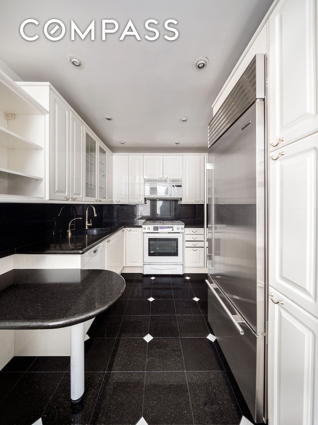 71 Park Ave Unit 12A, New York City, NY 10016 - kitchen featuring white appliances, granite tiled floors, dark countertops, white cabinets, and glass insert cabinets