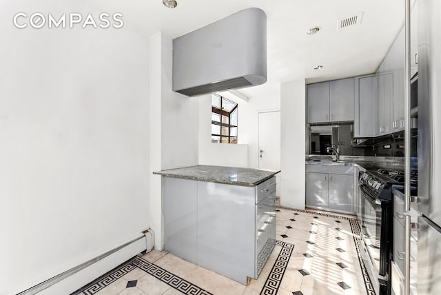40 Sutton Pl Unit 10M, New York City, NY 10022 - kitchen with a baseboard heating unit, inlaid floor details, black gas stove, gray cabinetry, and light tile patterned floors