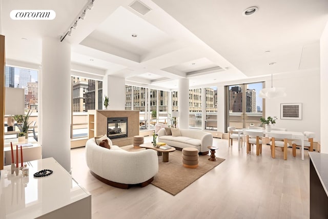 76 Madison Ave Unit Ph1, New York City, NY 10016 - living area featuring light wood-style floors, a city view, a multi sided fireplace, floor to ceiling windows, and coffered ceiling