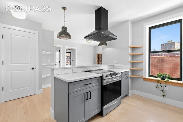 108 Division Ave Unit 22, New York City, NY 11211 - kitchen with stainless steel electric range oven, island range hood, gray cabinets, a peninsula, and light wood-style floors