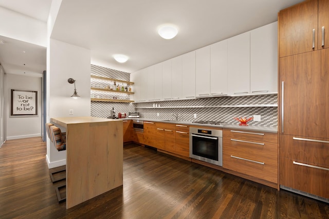 257 W 17th St Unit 2B, New York City, NY 10011 - kitchen featuring oven, modern cabinets, decorative backsplash, dark wood-style flooring, and light countertops