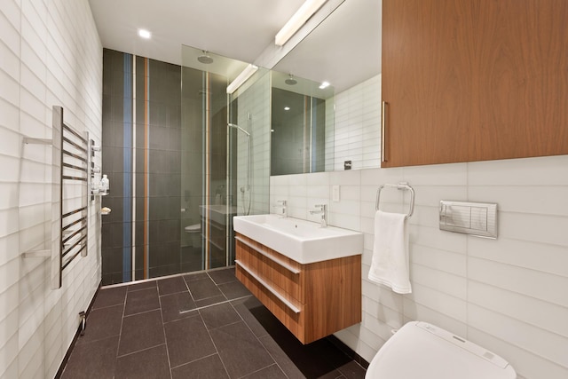 257 W 17th St Unit 2B, New York City, NY 10011 - bathroom featuring tile walls, a stall shower, vanity, a towel warming rack, and tile patterned floors