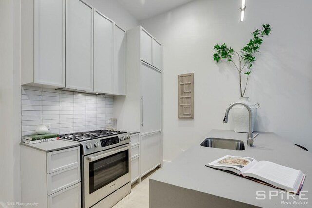 111 Montgomery St Unit 1N, New York City, NY 11225 - kitchen with stainless steel gas stove, tasteful backsplash, white cabinets, and light countertops