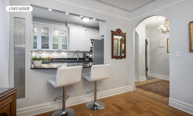 333 E 80th St Unit 3G, New York City, NY 10075 - kitchen featuring arched walkways, dark countertops, stainless steel fridge, a kitchen breakfast bar, and white cabinets