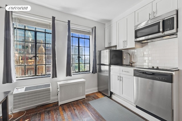 45 Tudor City Pl Unit 1002, New York City, NY 10017 - kitchen with stainless steel appliances, radiator, dark wood-style floors, white cabinetry, and decorative backsplash