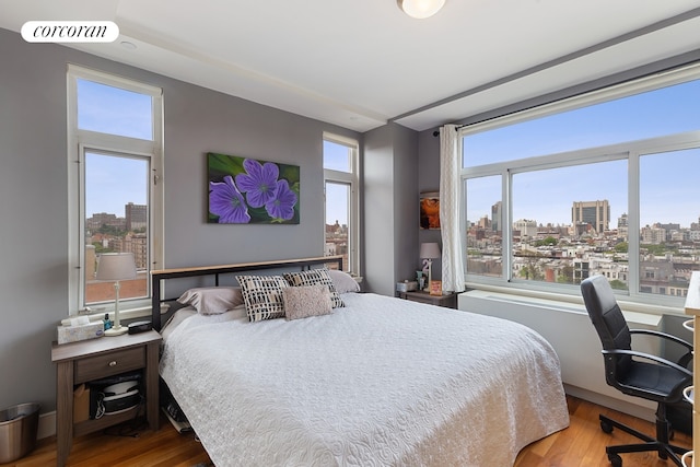 106 W 116th St Unit 10A, New York City, NY 10026 - bedroom with a skyline view, wood finished floors, and a desk