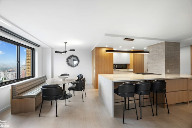 201 W 70th St Unit 24B, New York City, NY 10023 - kitchen with modern cabinets, backsplash, light wood-style floors, a kitchen bar, and recessed lighting