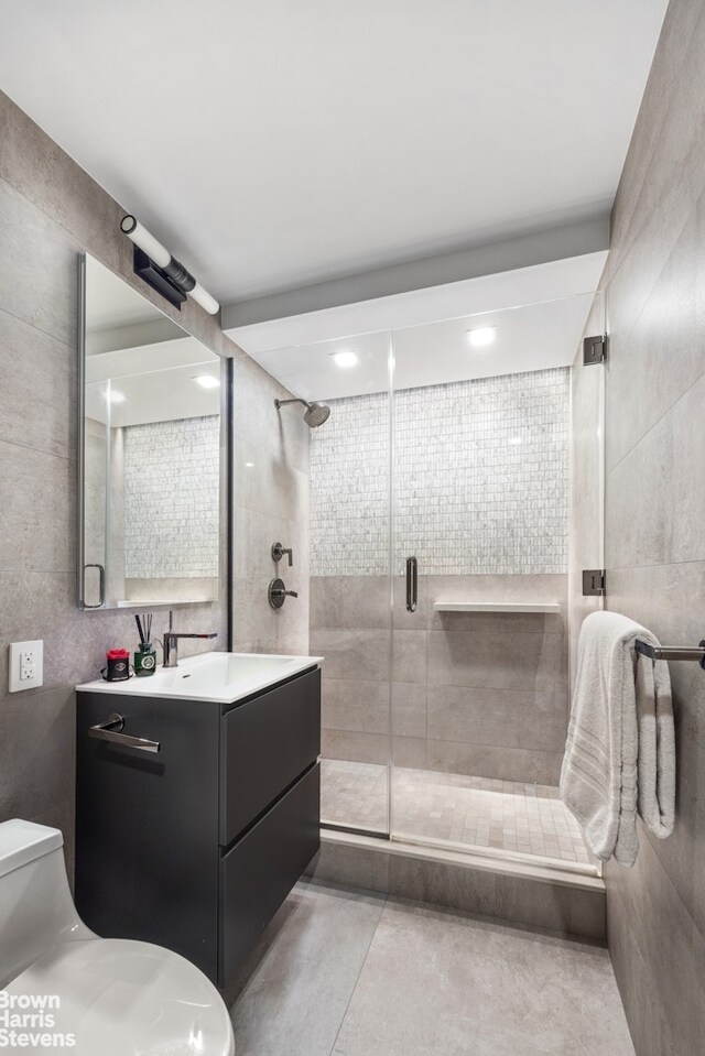 201 W 70th St Unit 24B, New York City, NY 10023 - bathroom with vanity, a stall shower, tile walls, and tile patterned flooring