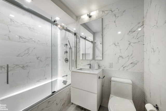 201 W 70th St Unit 24B, New York City, NY 10023 - bathroom featuring combined bath / shower with glass door, vanity, and tile walls