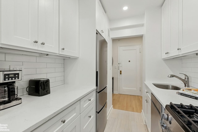 130 8th Ave Unit 6E, New York City, NY 11215 - kitchen with stainless steel appliances, white cabinetry, backsplash, recessed lighting, and light stone countertops