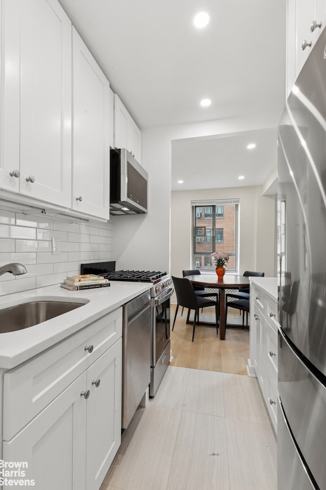 130 8th Ave Unit 6E, New York City, NY 11215 - kitchen featuring stainless steel appliances, light countertops, tasteful backsplash, white cabinets, and recessed lighting