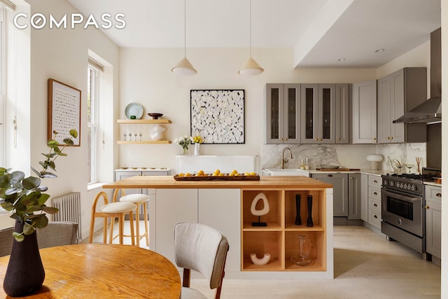 252 Greene Ave Unit 1B, New York City, NY 11238 - kitchen featuring high end range, gray cabinetry, wall chimney exhaust hood, butcher block counters, and open shelves