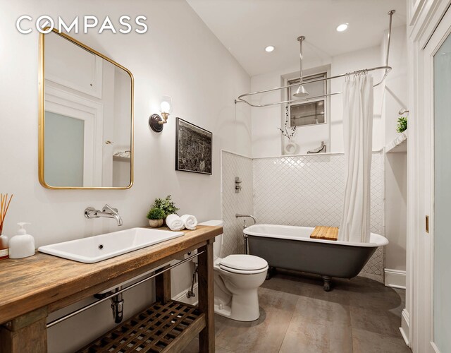 252 Greene Ave Unit 1B, New York City, NY 11238 - bathroom featuring a soaking tub, tile walls, a shower with shower curtain, wood finished floors, and vanity