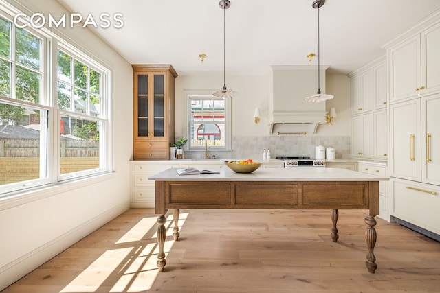 320 E 18th St Unit 5, New York City, NY 11226 - kitchen with light countertops, light wood finished floors, white cabinets, glass insert cabinets, and a center island