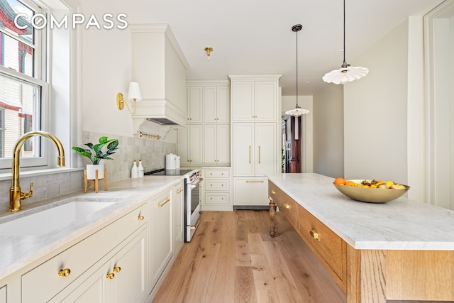 320 E 18th St Unit 5, New York City, NY 11226 - kitchen with electric range, light wood-style floors, backsplash, and white cabinetry