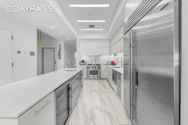 124 E 13th St Unit 3, New York City, NY 10003 - kitchen featuring high quality appliances, beverage cooler, modern cabinets, white cabinetry, and light countertops