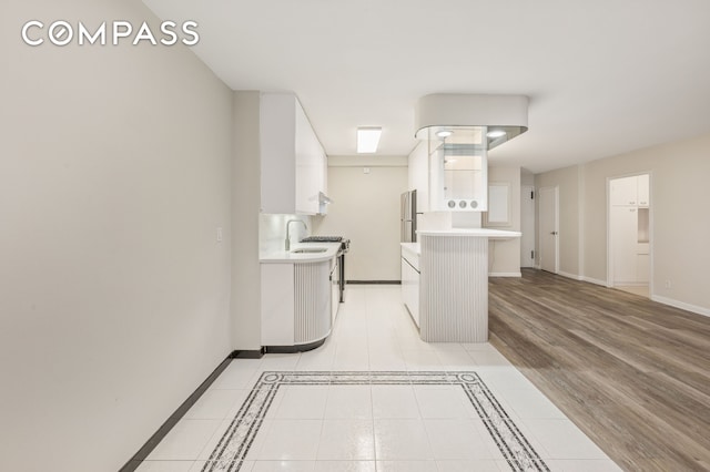 211 E 53rd St Unit 7C, New York City, NY 10022 - kitchen featuring light countertops, white cabinets, freestanding refrigerator, light tile patterned floors, and a kitchen breakfast bar