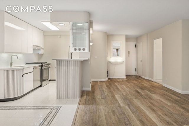 211 E 53rd St Unit 7C, New York City, NY 10022 - kitchen with stove, under cabinet range hood, light countertops, white cabinets, and light wood finished floors