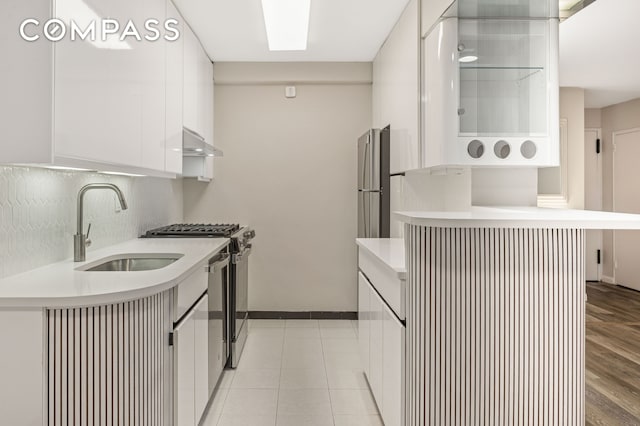 211 E 53rd St Unit 7C, New York City, NY 10022 - kitchen featuring stainless steel gas range oven, light countertops, white cabinetry, under cabinet range hood, and backsplash