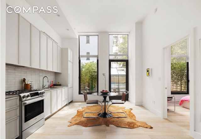 111 Montgomery St Unit B1, New York City, NY 11225 - kitchen with gas stove, tasteful backsplash, light wood-style flooring, white cabinets, and light countertops