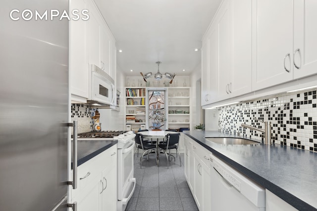 525 E 89th St Unit 4Hj, New York City, NY 10128 - kitchen with white appliances, a chandelier, dark countertops, white cabinets, and recessed lighting